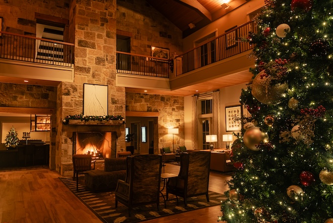 The lobby of Hyatt Regency Lost Pines Resort & Spa with a fireplace and Christmas tree. 