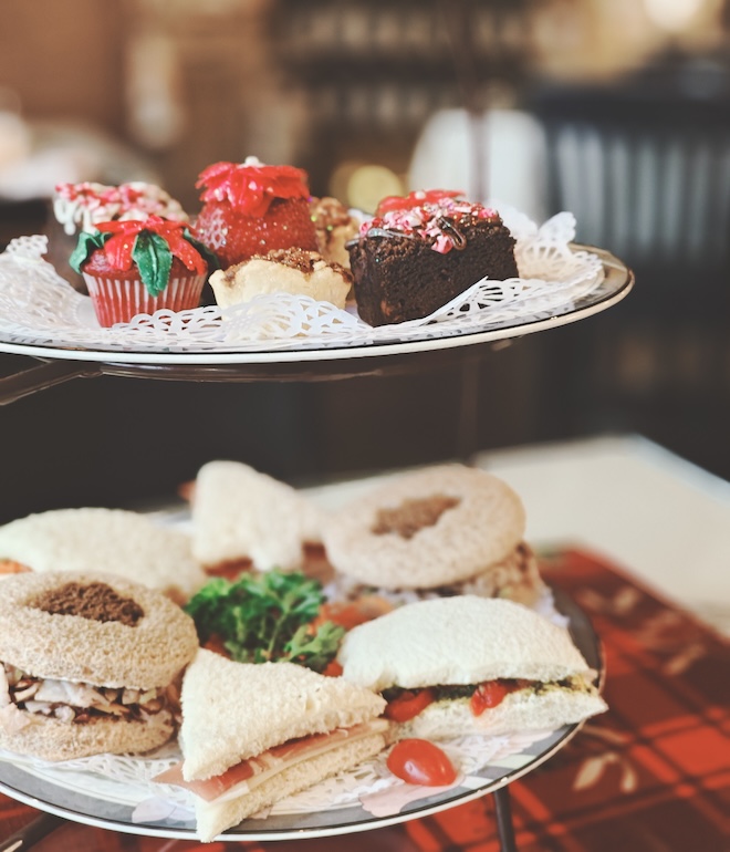 Small sandwiches and pastries on a two-tier tray from McHughTEA Room & Gifts. 