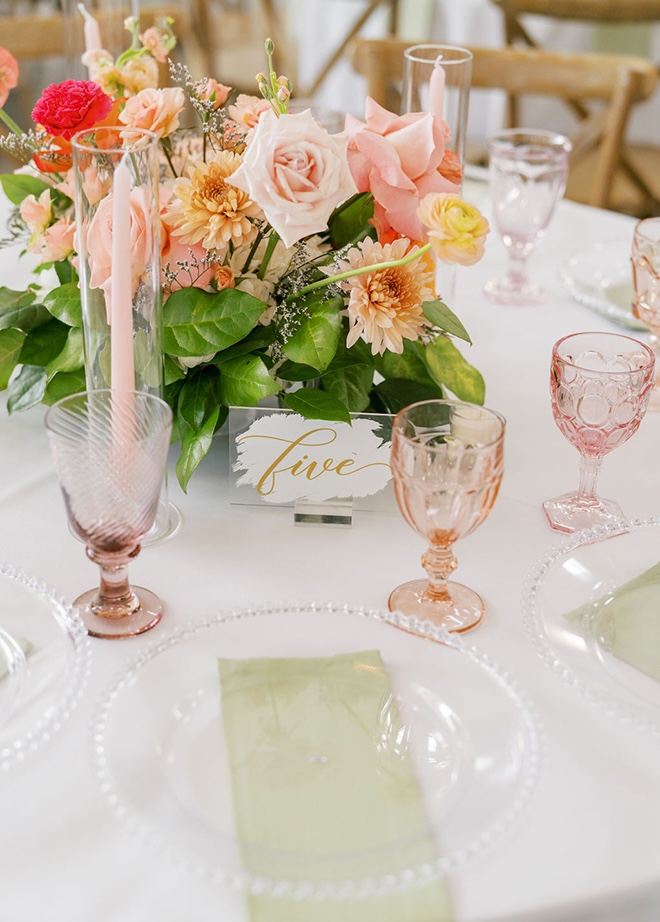 Pink, orange and peach florals decorate the reception tables at the colorful farmhouse wedding.