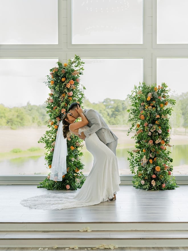 The couple share their first kiss on the alter under a broken floral arch. 