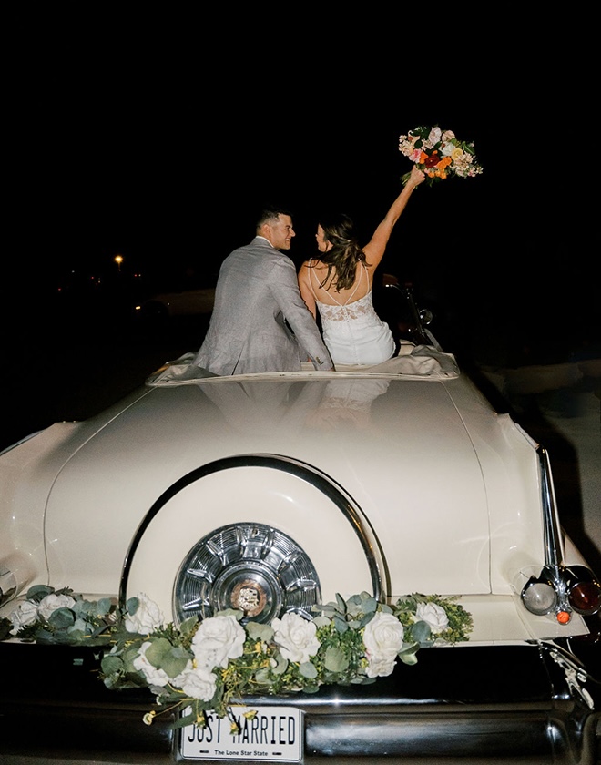 The bride and groom ride off in a getaway car from their colorful farmhouse wedding. 