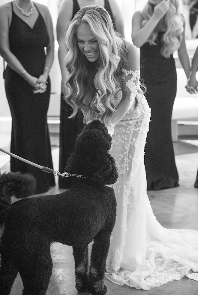 The bride pets a Golden Doodle dog before her wedding ceremony in Houston. 