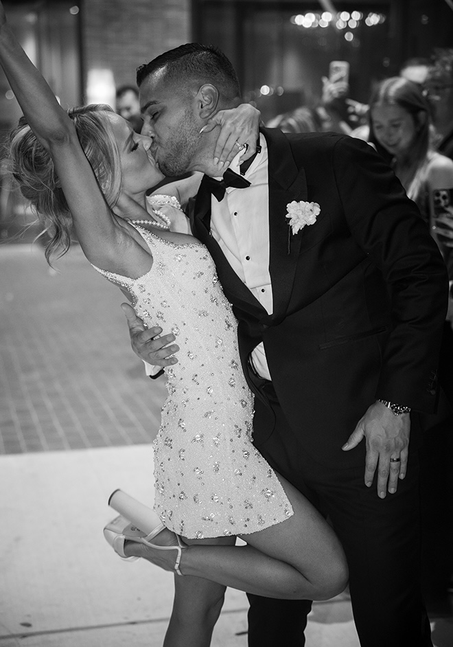 The bride and groom share a kiss as the exit their wedding reception. 