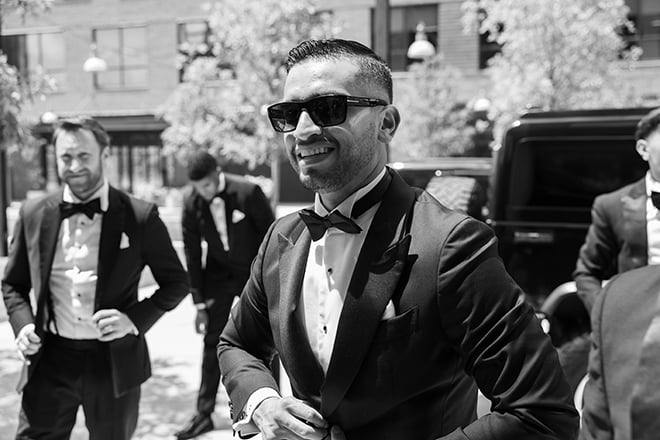 The groom buttons up his tuxedo for his wedding day. 