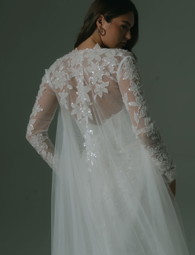 A sparkly floral-embossed tulle cape and sleeves. 