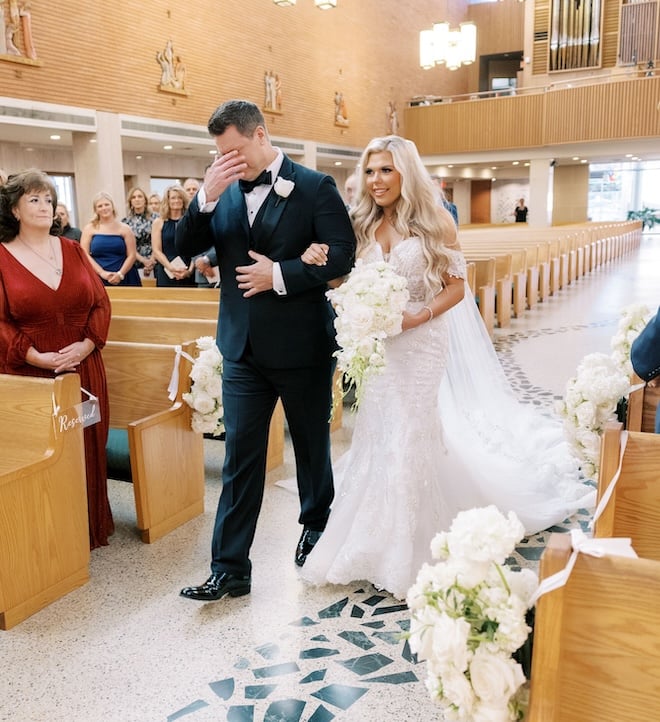 The bride's father wiping his tears away while walking her down the aisle. 