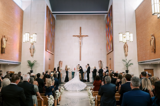 The bride and groom kissing at the altar. 