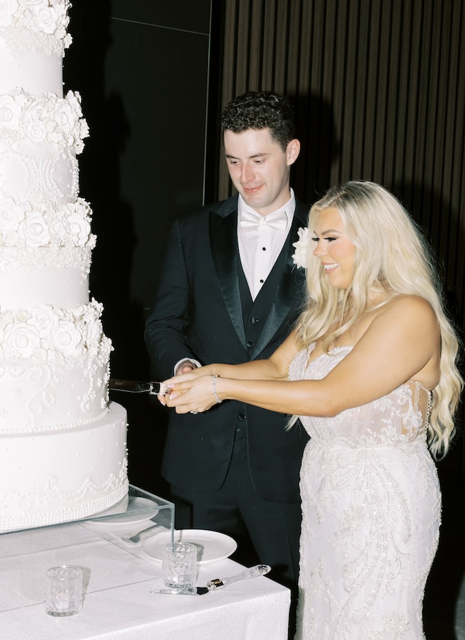 The bride and groom cutting their large white wedding cake. 