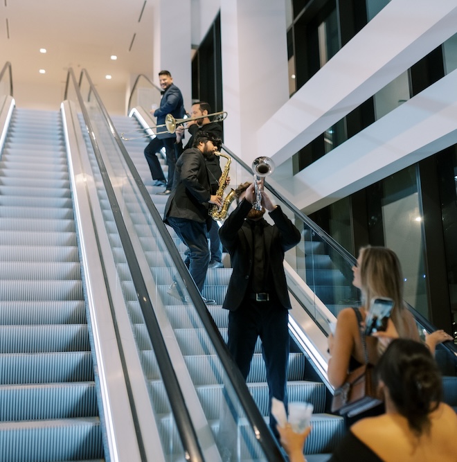 Men playing the trumpets up the escalator at the Thompson Houston, by Hyatt. 