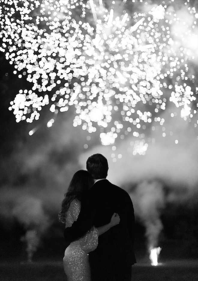 The couple looks up into the night sky to watch the fireworks.