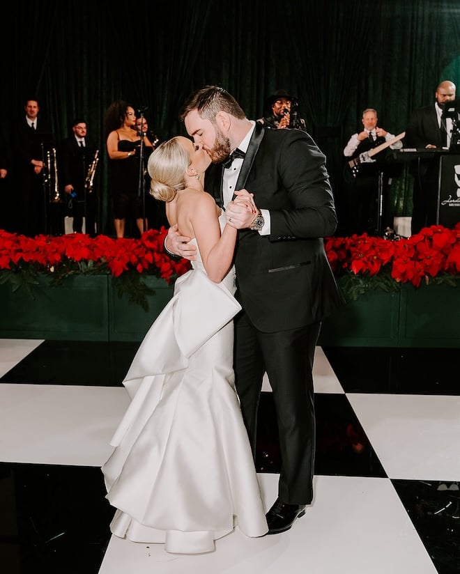 The bride and groom kissing on the black and white checkered dance floor. 