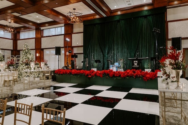 A black-and-white dance floor with poinsettias lining the green stage. 