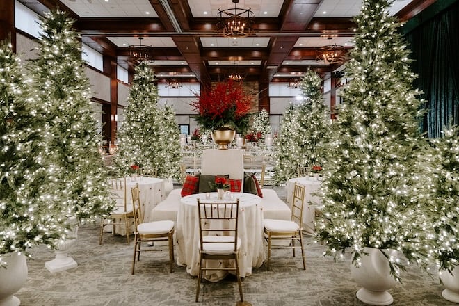 The ballroom lined with tall Christmas trees and red decor. 