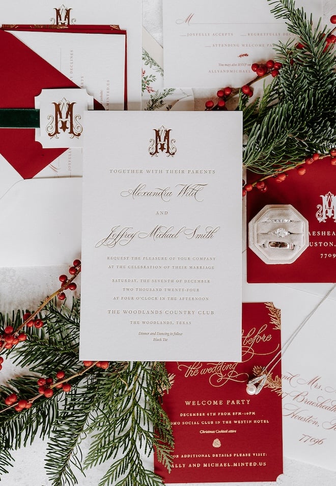 A flatlay of the invitation suite with white, red and gold stationery. 