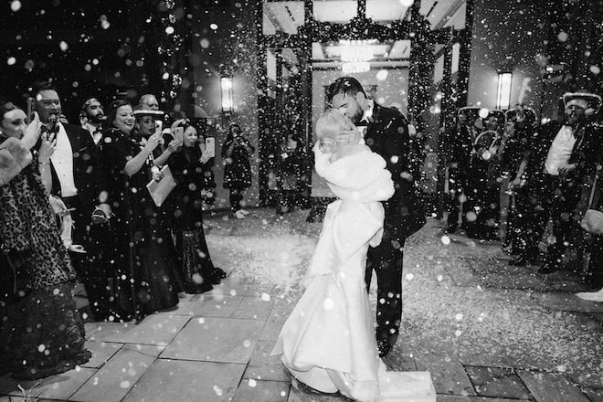 The bride and groom kissing during their exit with snow surrounding them. 