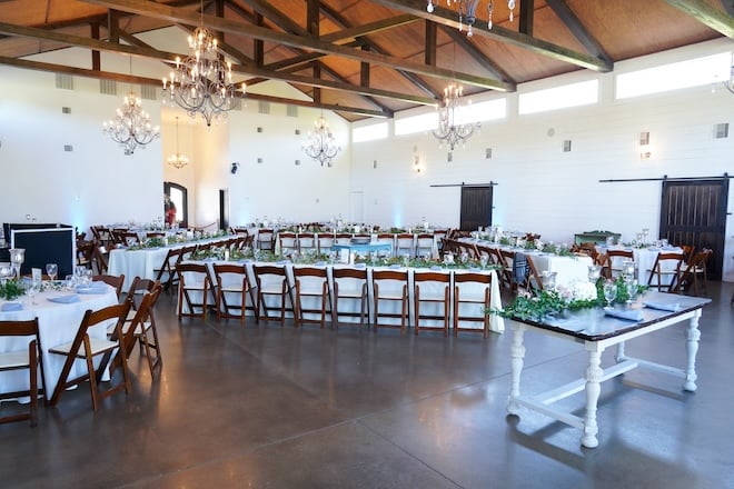 The reception space at Venue 311 decorated with long reception tables with white linens and wooden chairs. 