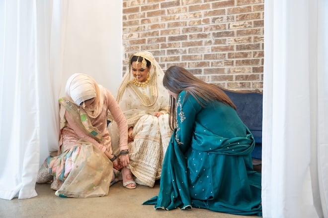 The bride and two women helping her get ready. 