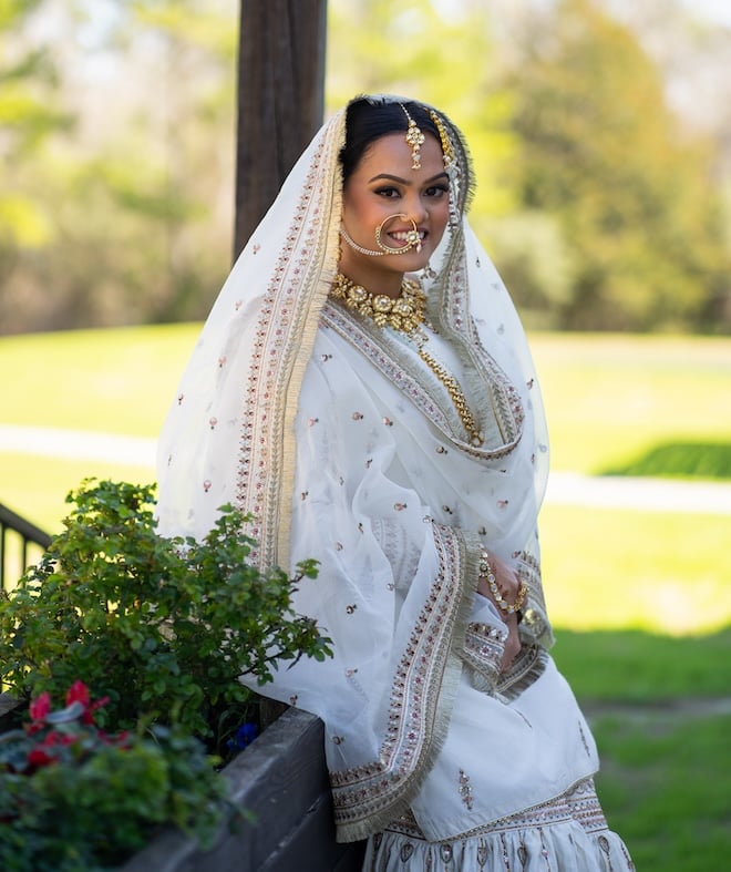 The bride smiling with greenery behind her. 