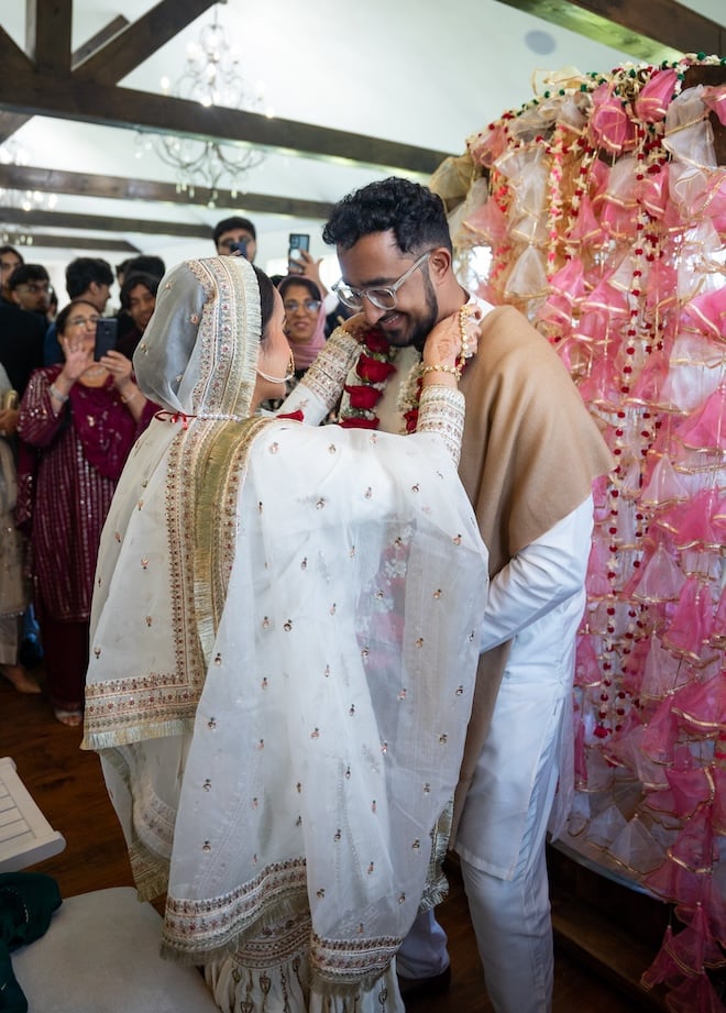 The bride putting a Hajj necklace of roses on the groom. 