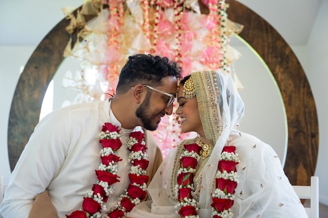 The bride and groom smiling with their foreheads pressed together during their ceremony. 