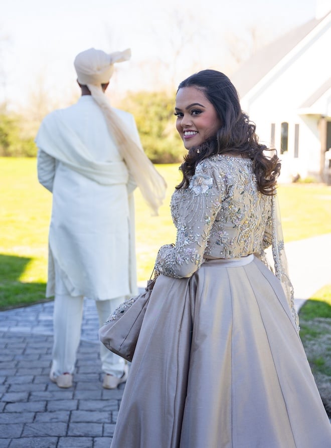 The bride looking back at the camera smiling before she reveals her reception outfit to the groom. 