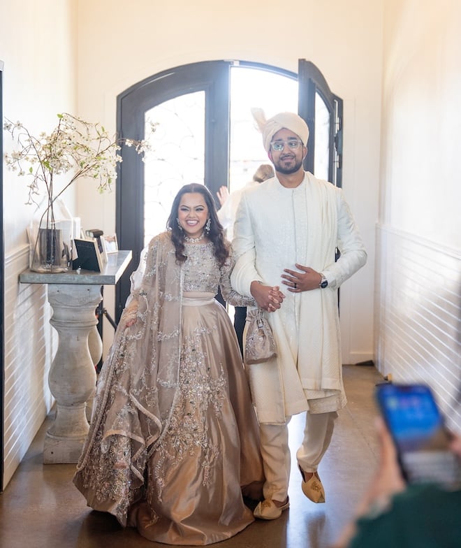 The bride and groom holding hands while entering the reception space. 