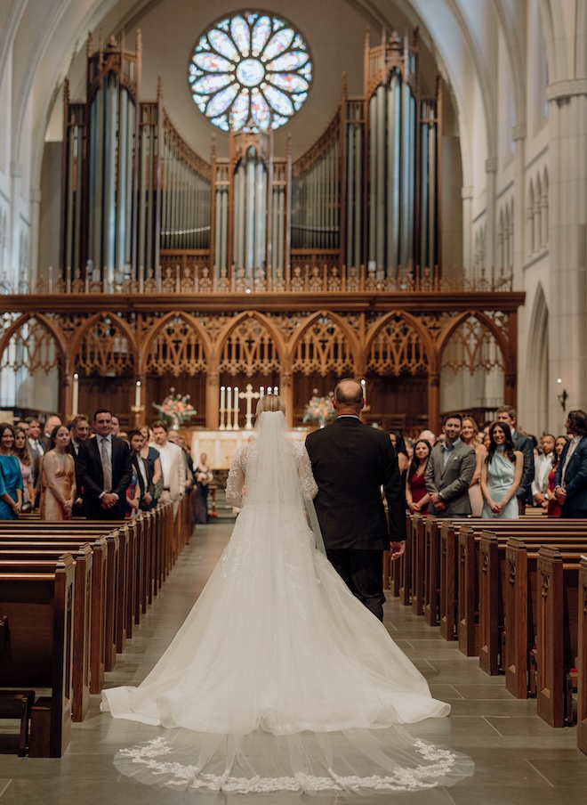 The bride and her father walking down the aisle at a traditional church. 