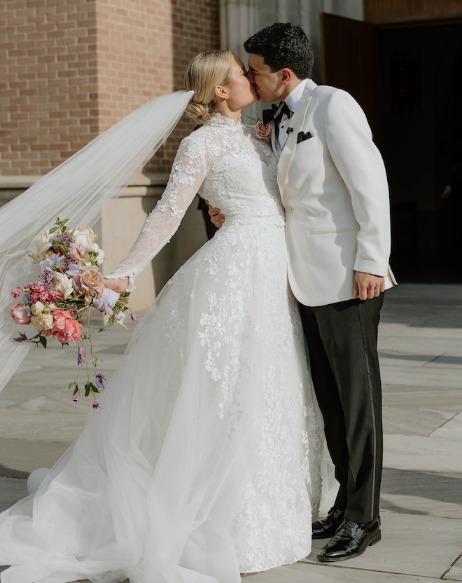 A bride and groom kissing in front of the church. 