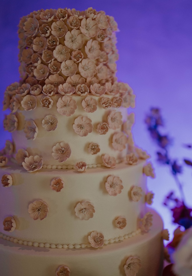 A four-tier white cake with pink florals. 