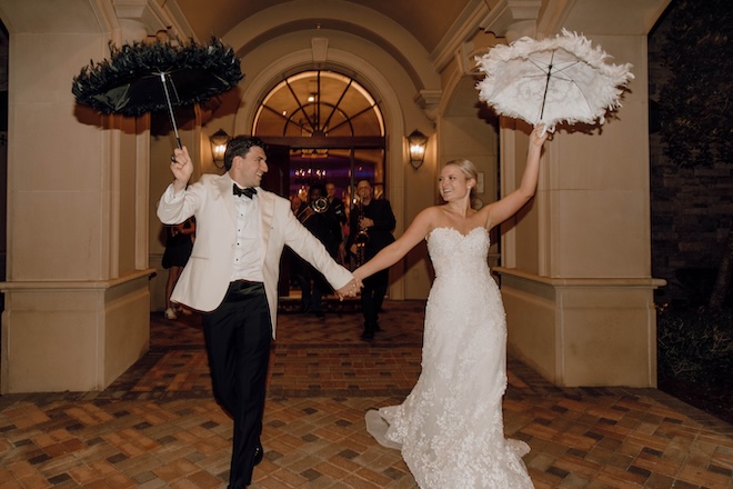 The bride and groom holding up black and white umbrellas during their Second Line Exit, a New Orleans-inspired wedding tradition. 