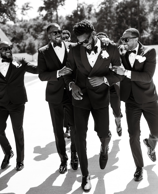 The groom walking and laughing with his groomsmen. 