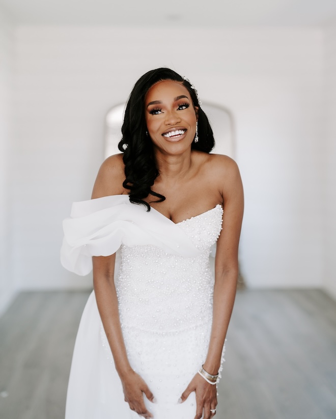 The bride wearing a strapless pearl wedding gown and smiling. 