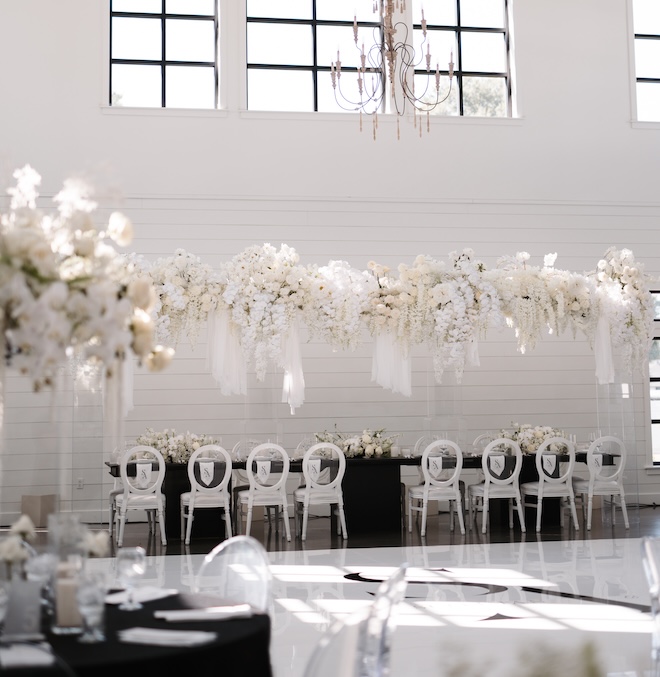 White floral arrangement hanging over the family-style reception table. 