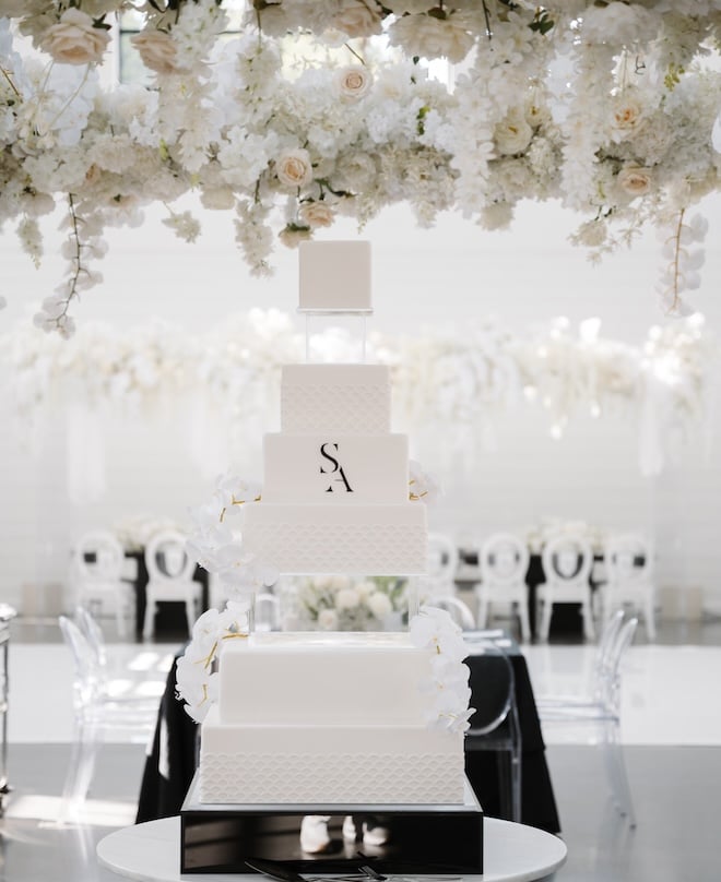 An eight-tier wedding cake with a black monogram. 