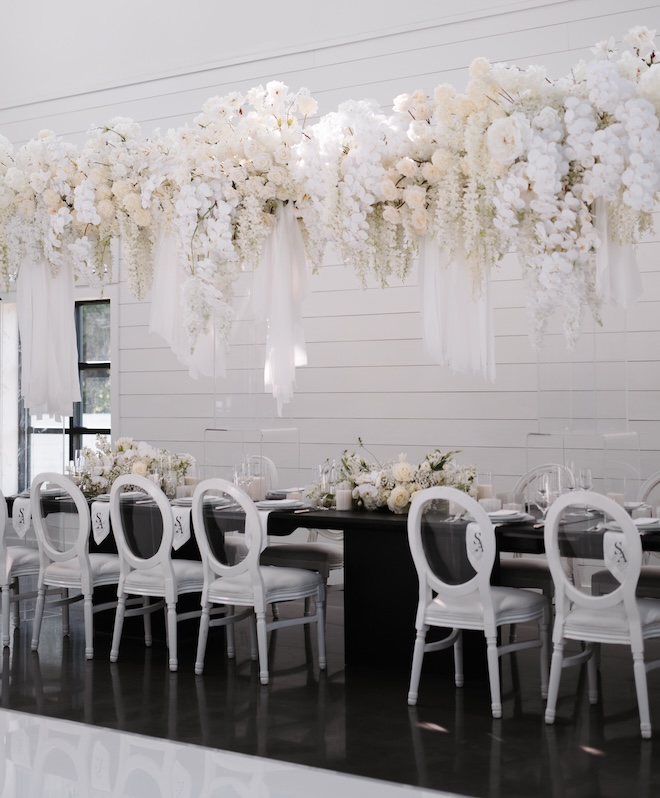 White floral arrangement hanging over the family-style reception table. 