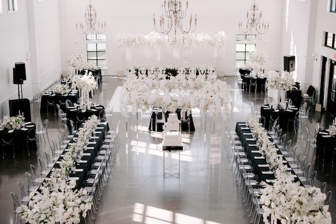 The reception space decorated with black linens and white florals and decor. 