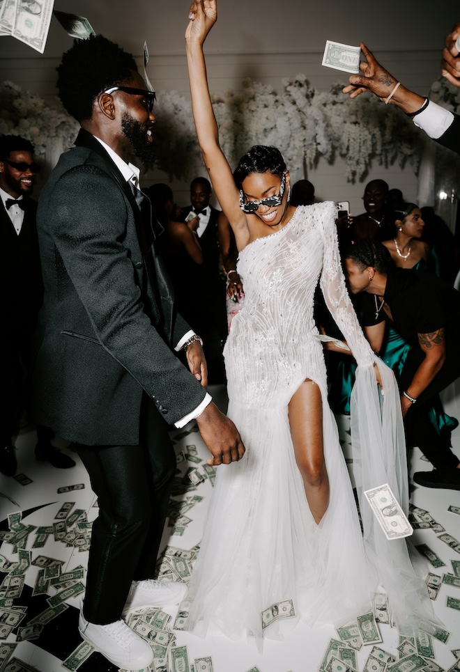 The bride and groom on the dance floor with dollar bills flying around. 