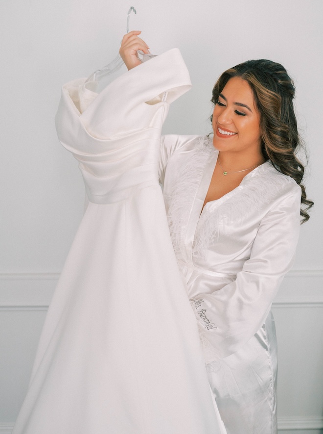 The bride holds up her wedding dress before walking down the aisle. 