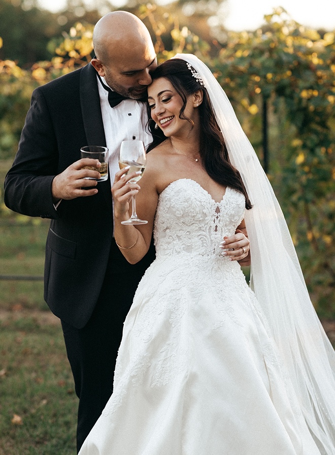 The bride and groom cheers with cocktails outside their wedding venue. 