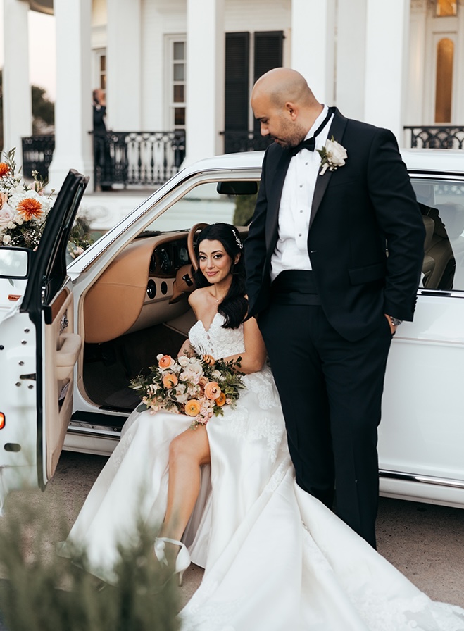 The bride and groom pose next to a vintage white car from Houston Classic Wedding Cars. 