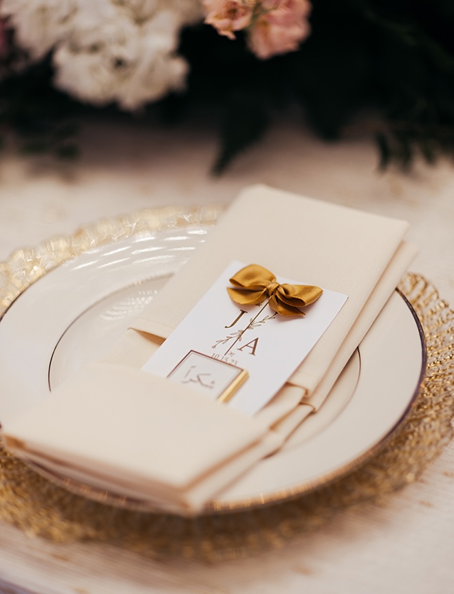 Wedding stationery with the couple initials are placed on plates at the wedding reception.