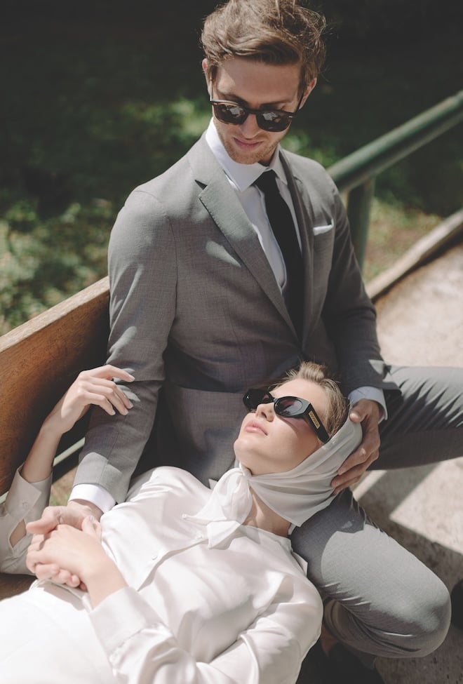 A woman wearing all white resting her head on a man's lap. 