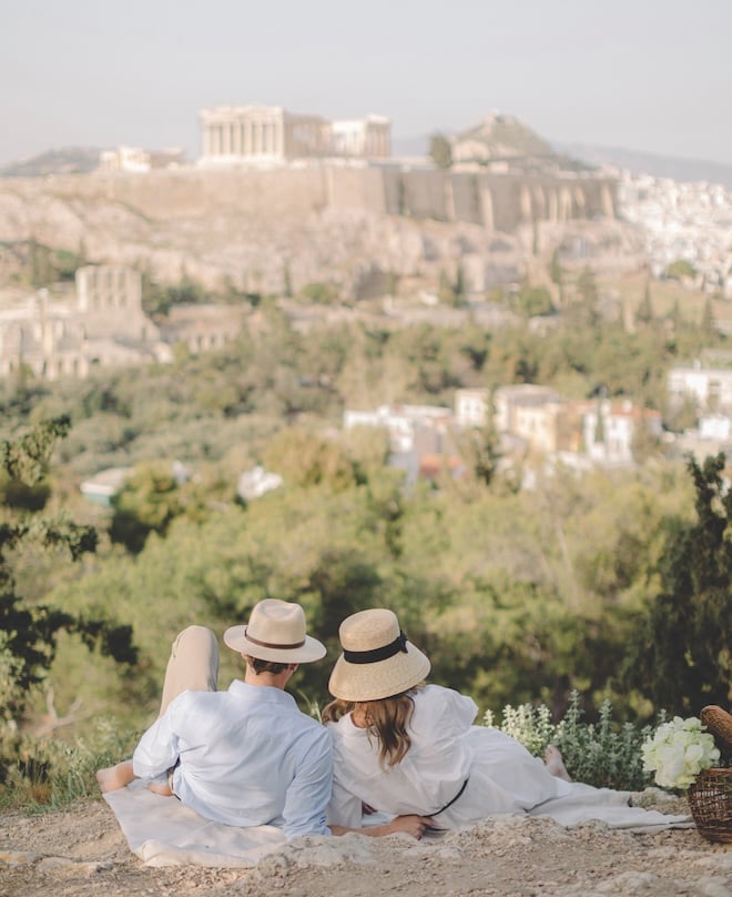 A couple laying on a blanket overlooking the scenic views of Athens, Greece. 