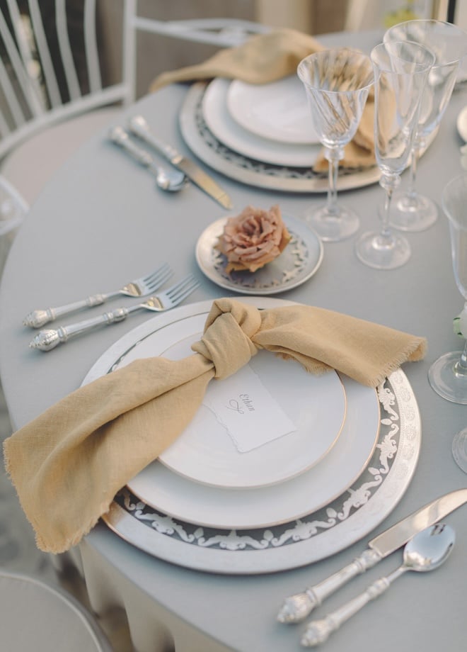 A table set for two with beige napkins and white plates. 