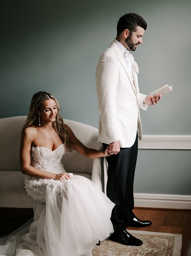 The groom reads private vows to the bride while holding her hand. 