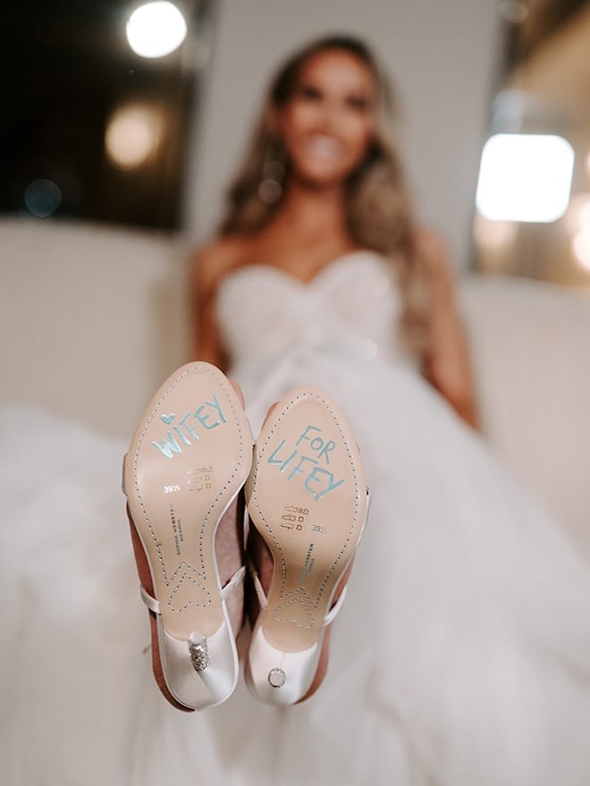 The bride wears Sophia Webster heels with soles that say Wifey for Lifey on the bottom. 