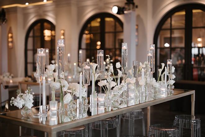 Bud vases and taper candles decorate family style tables at the chic Houston wedding. 