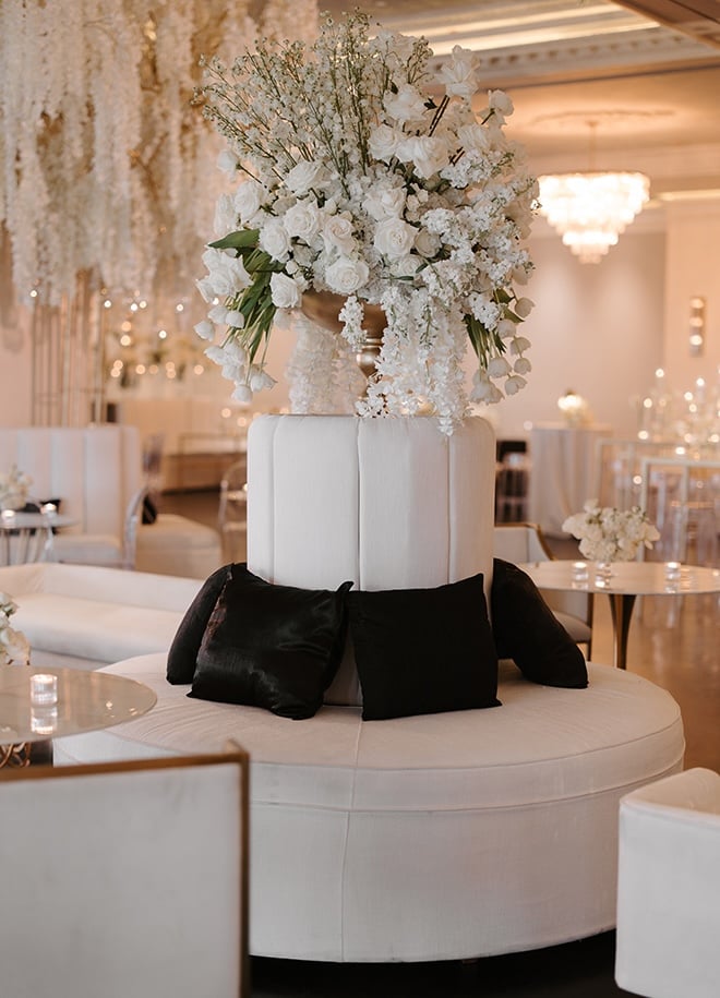 White lounge seating and floral arrangements detail the reception venue. 