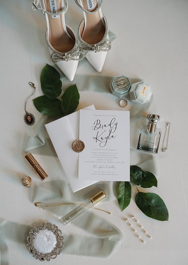 Mandi Roach Photography captures a flat lay of the couple's wedding invitation, perfume, Aggie rings, shoes and jewelry. 