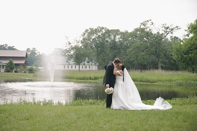 The couple share a kiss in an open field outside their wedding venue.